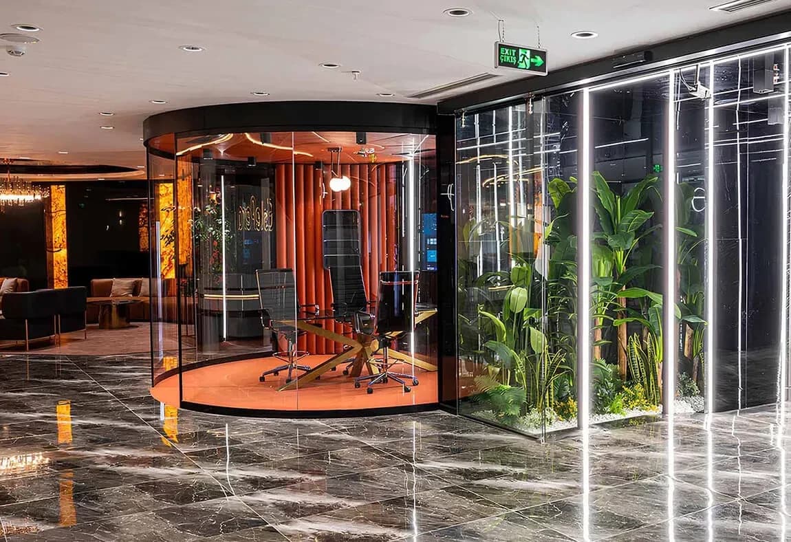 Couloir en marbre desservant une salle de consultation vitrée aux parois orange et un mur de plantes