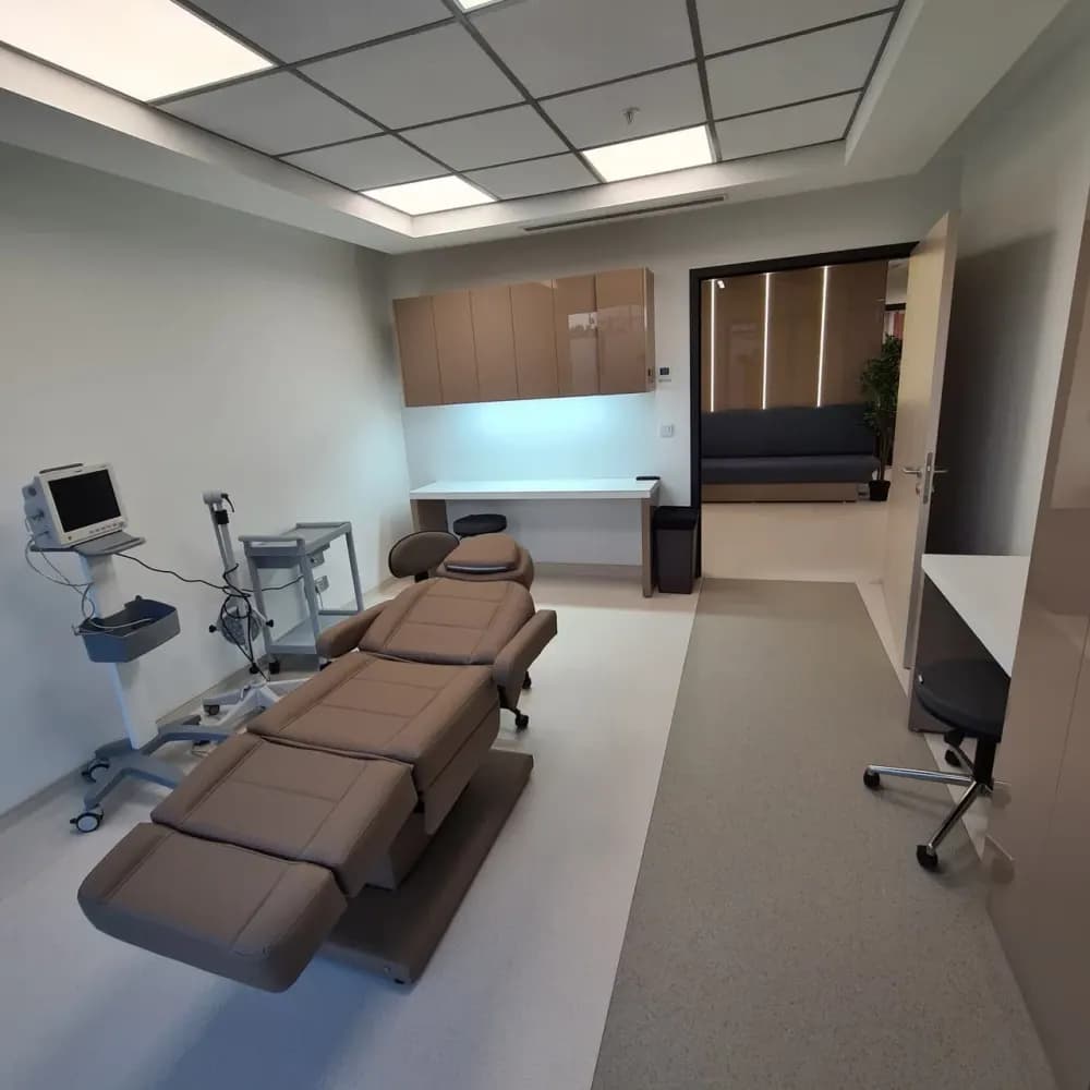 Salle d'examen claire avec fauteuil de soins réglable, moniteur médical et plan de travail