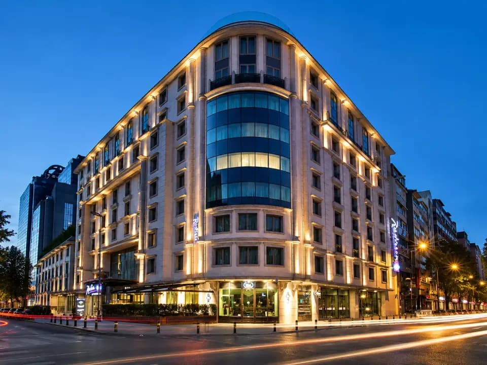 Façade éclairée de l'hôtel 5 étoiles, à l'angle d'une avenue du quartier de Şişli, à la tombée du jour