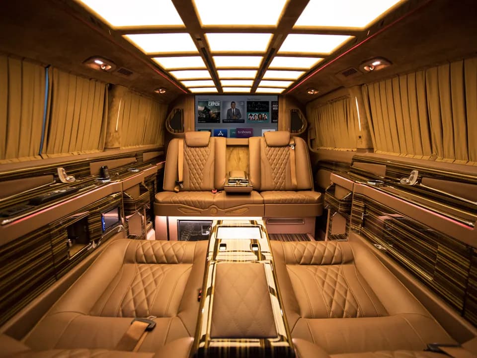 Intérieur du Mercedes Vito : sièges en cuir beige matelassés, écrans et éclairage de plafond